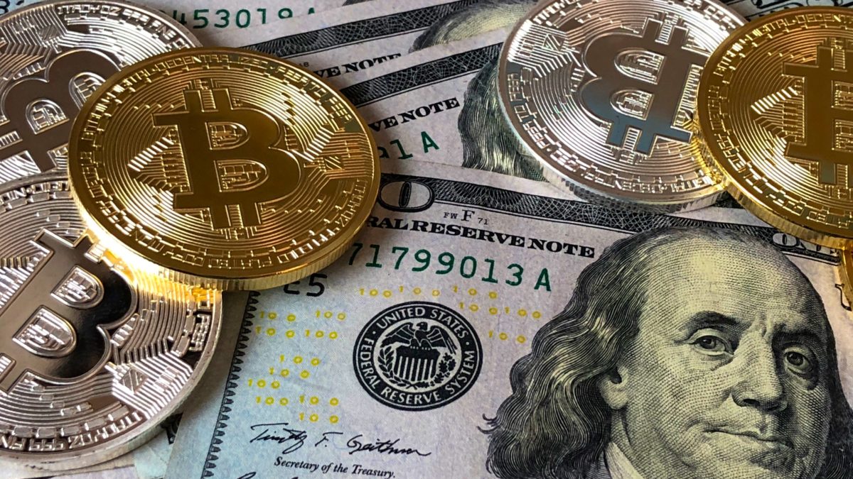 Bitcoins and US Currency scattered on a table